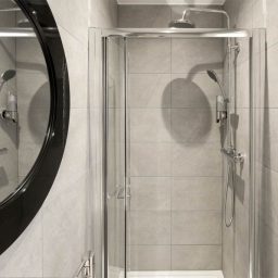 Modern bathroom with shower cubicle and tiled walls in neutral tones.