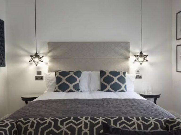 Modern bedroom with a double bed, decorative pillows, and stylish lighting fixtures.