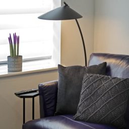 Purple sofa with textured cushions and reading lamp.