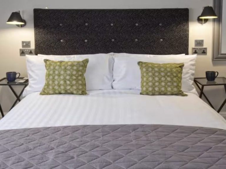 Neatly arranged bedroom with a double bed, patterned cushions, and bedside tables.