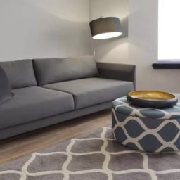 Modern living room featuring a grey sofa, patterned rug, and circular coffee table.