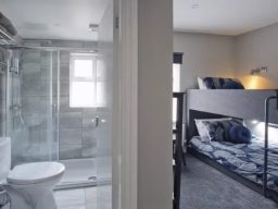 A modern room featuring a bunk bed and a bathroom with a glass shower.