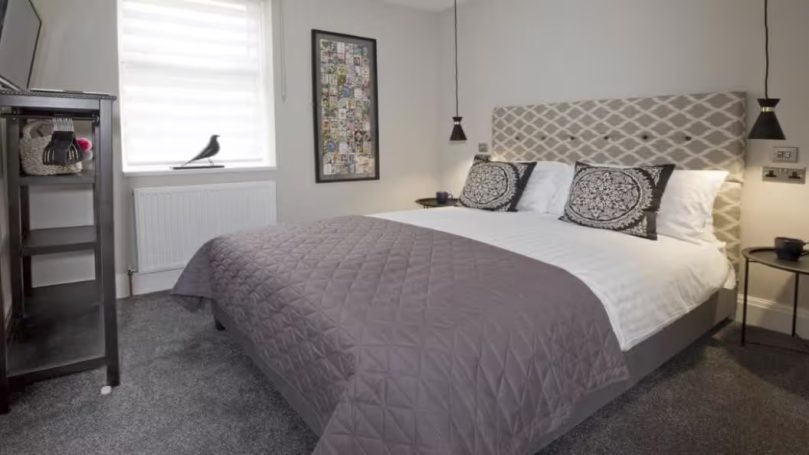 Modern bedroom with a large bed, patterned headboard, and minimalist decor.