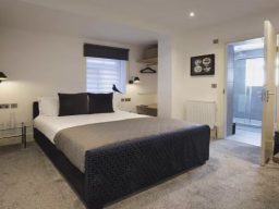 Modern bedroom with a double bed, grey decor, and an en-suite bathroom.