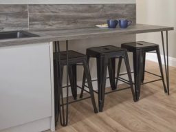Three black stools lined up under a grey countertop in a modern kitchen setting.