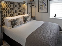 Modern bedroom with a designer headboard, decorative pillows, and large double bed.