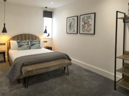 Modern bedroom with a bed, artwork on the walls, and a stylish bookshelf.