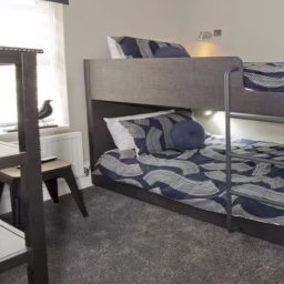 Bunk bed in a modern bedroom with patterned bedding and a small desk.