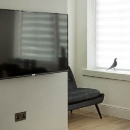 A sleek television mounted on a wall beside a window.