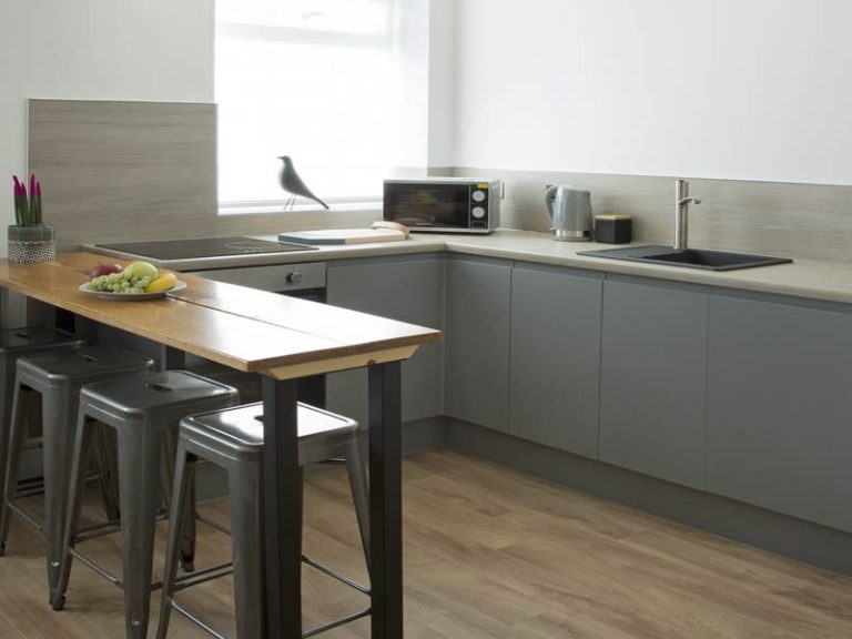 Modern kitchen with grey cabinets, a wooden dining table, and bar stools.