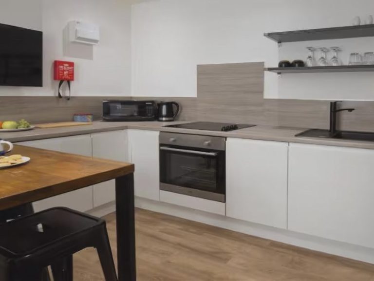 Modern kitchen with an oven, microwave, and dining table set with plates and utensils.