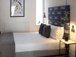 Modern bedroom with a double bed, stylish headboard, and artwork on the wall.