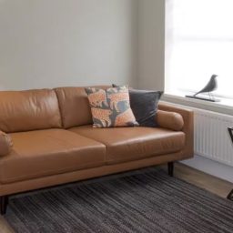 A brown leather sofa with decorative cushions in a modern living room setting.