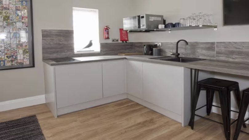 Modern kitchen featuring grey cabinets, a sink, and stainless steel appliances.