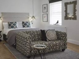 Stylish bedroom with a patterned sofa, bed, and decorative art on the walls.